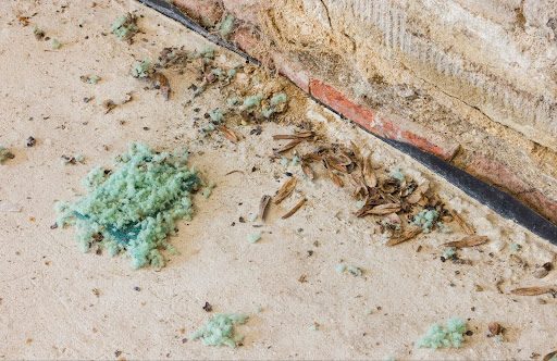 Green insulation and other debris outdoors on concrete